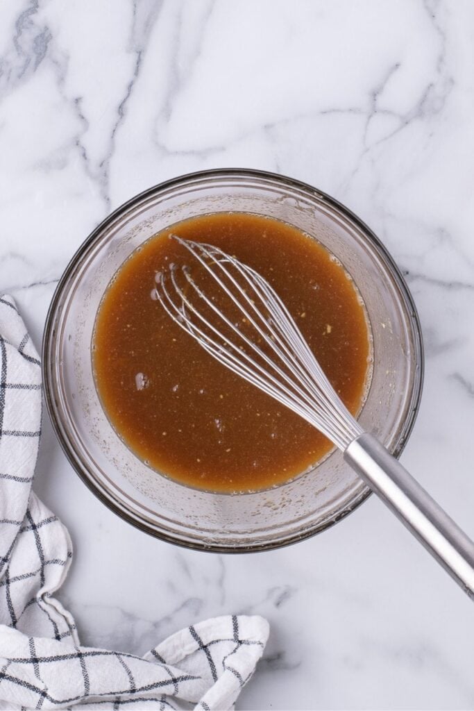 Ingredients for ham glazed whisked together in a glass bowl.