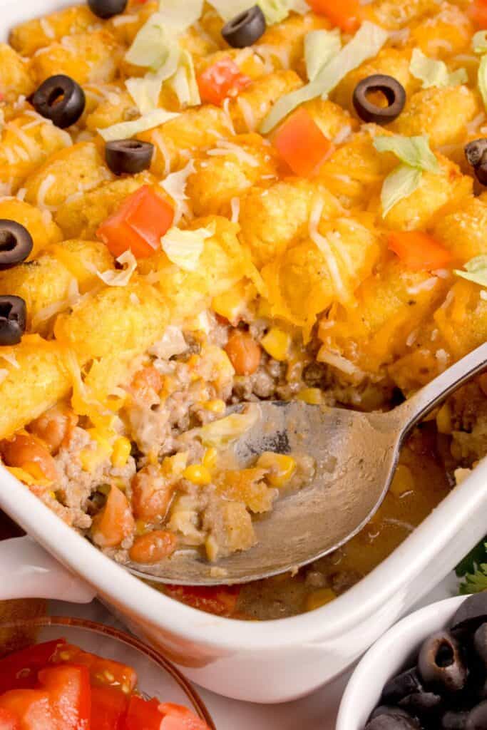 A serving of taco tater tot casserole have been removed from the baking dish to show the interior.
