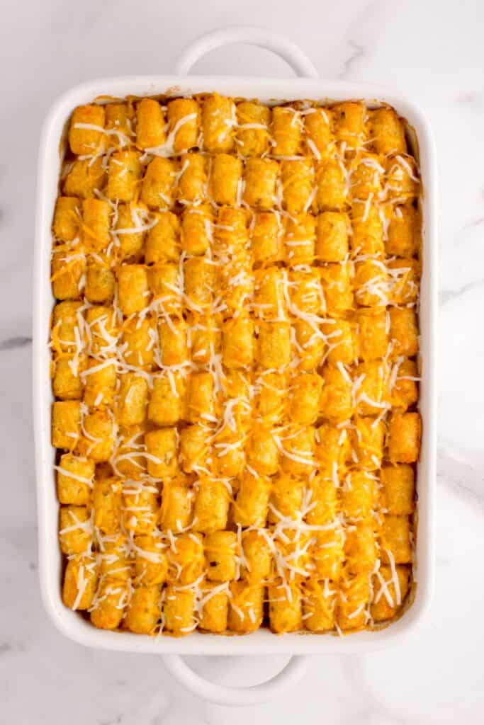 Par cooked casserole is sprinkled with a light layer of shredded cheese.