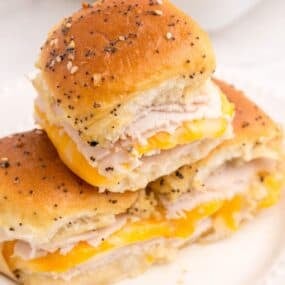 A stack of 3 turkey sliders on a white dinner plate.