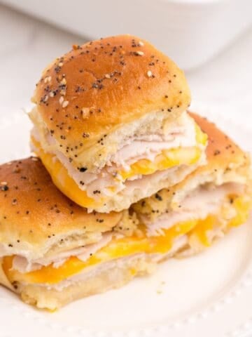 A stack of 3 turkey sliders on a white dinner plate.