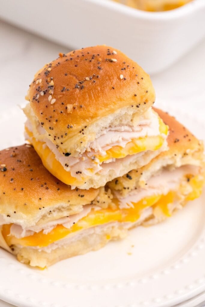 A stack of 3 turkey sliders on a white dinner plate.