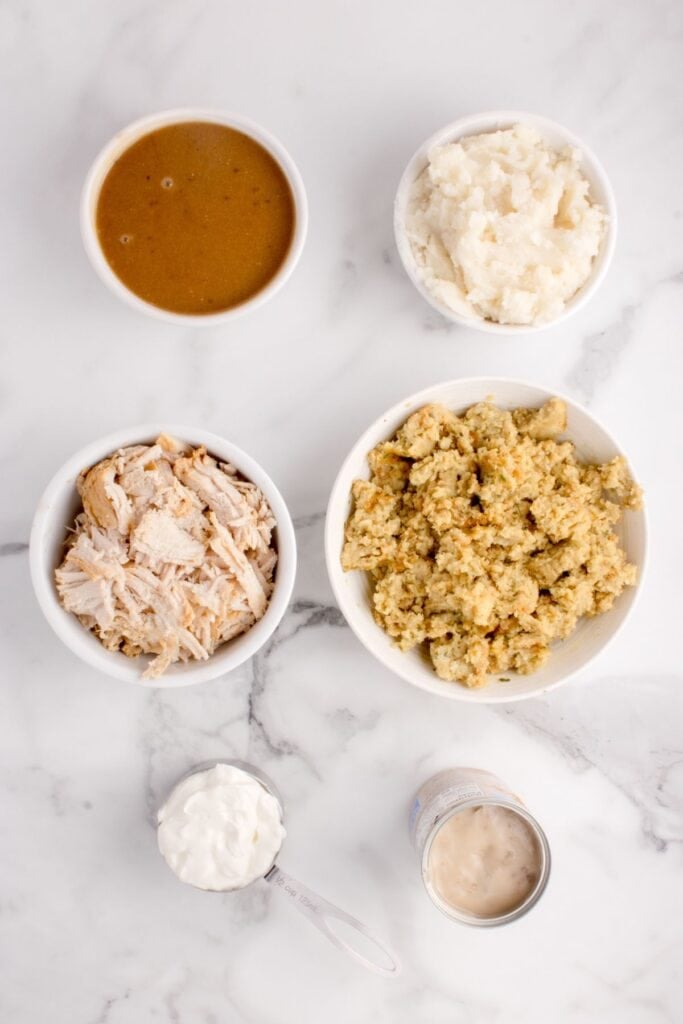 Ingredients for turkey stuffing casserole: mashed potatoes, cooked turkey, cream of mushroom soup, gravy, sour cream, and stuffing.