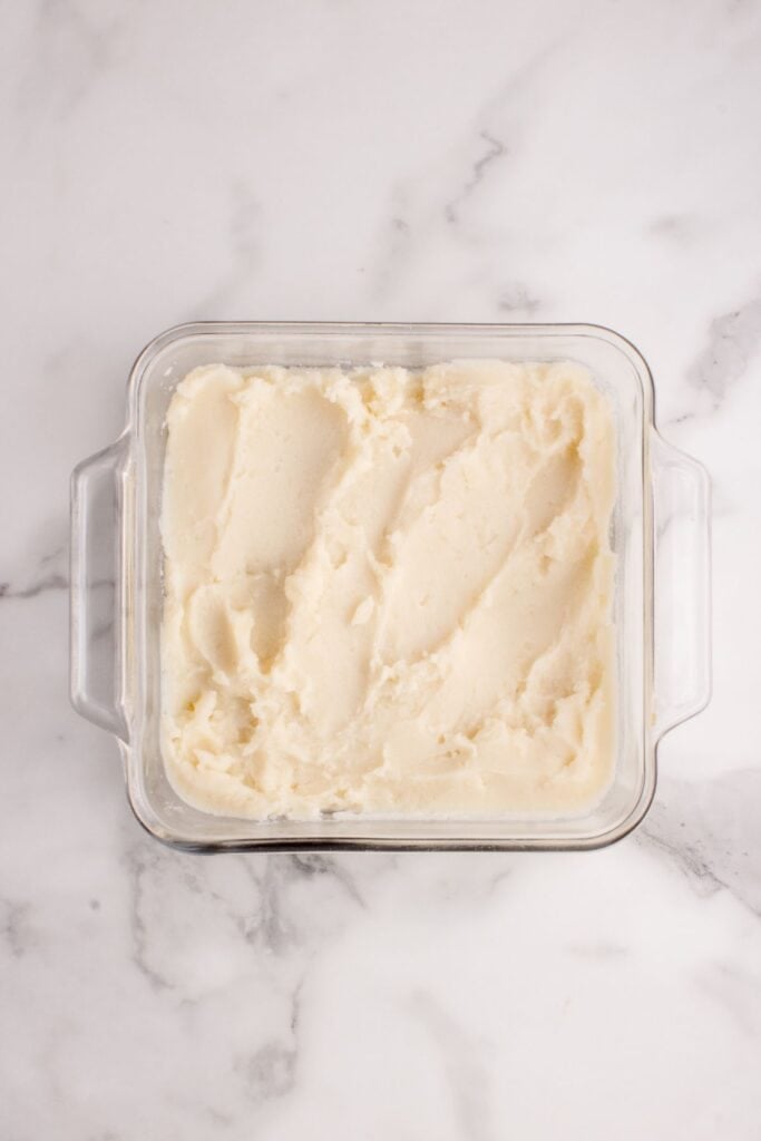 Mashed potatoes layering the bottom of a baking dish.