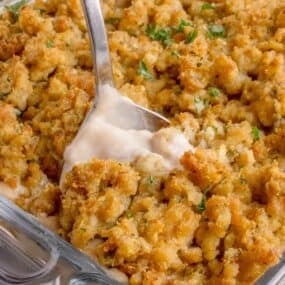 A serving spoon is scooping out a helping of casserole.
