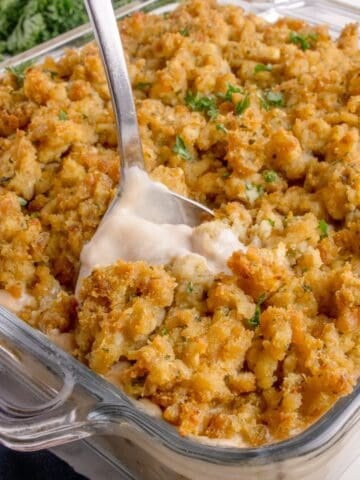 A serving spoon is scooping out a helping of casserole.