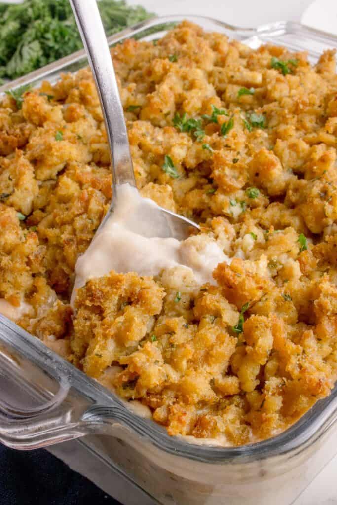 A serving spoon is scooping out a helping of casserole.