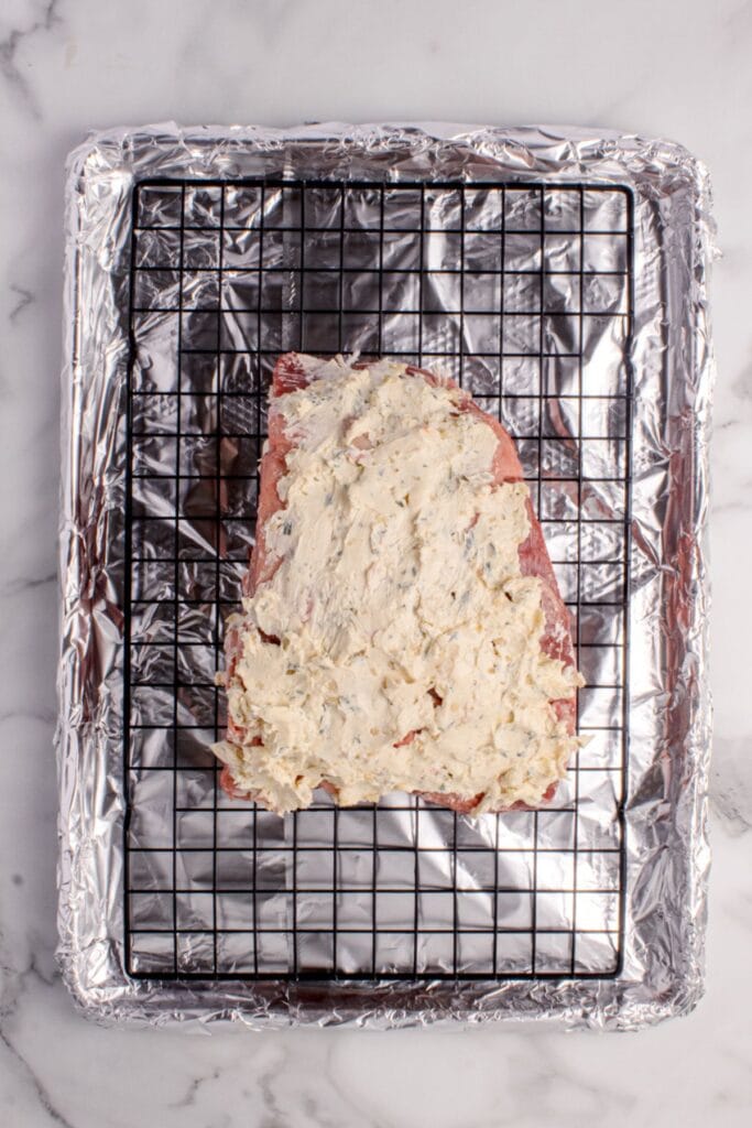 Raw prime rib cut smothered in butter and herb mixture.