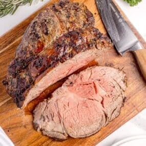 Sliced prime rib on a wooden cutting board.