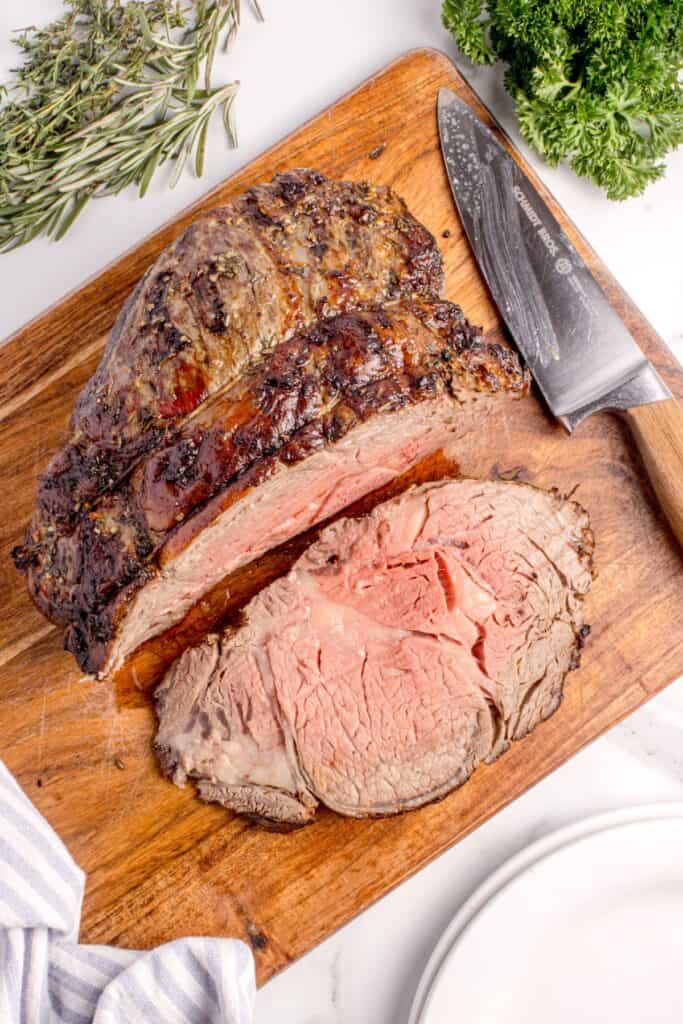 Sliced prime rib on a wooden cutting board.
