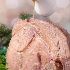 Ham shank drippings being poured over the top of the ham.