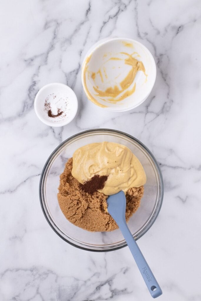 Mixing bowl with brown sugar, ground cloves, and mustard.