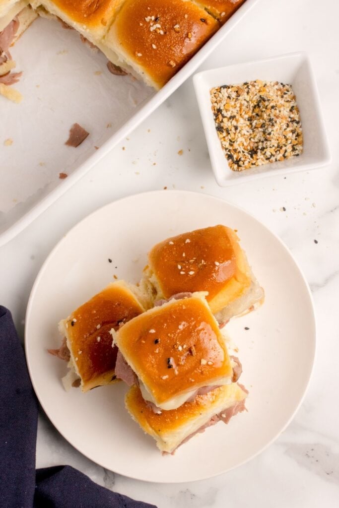 Four roast beef sliders stacked on a white dinner plate.