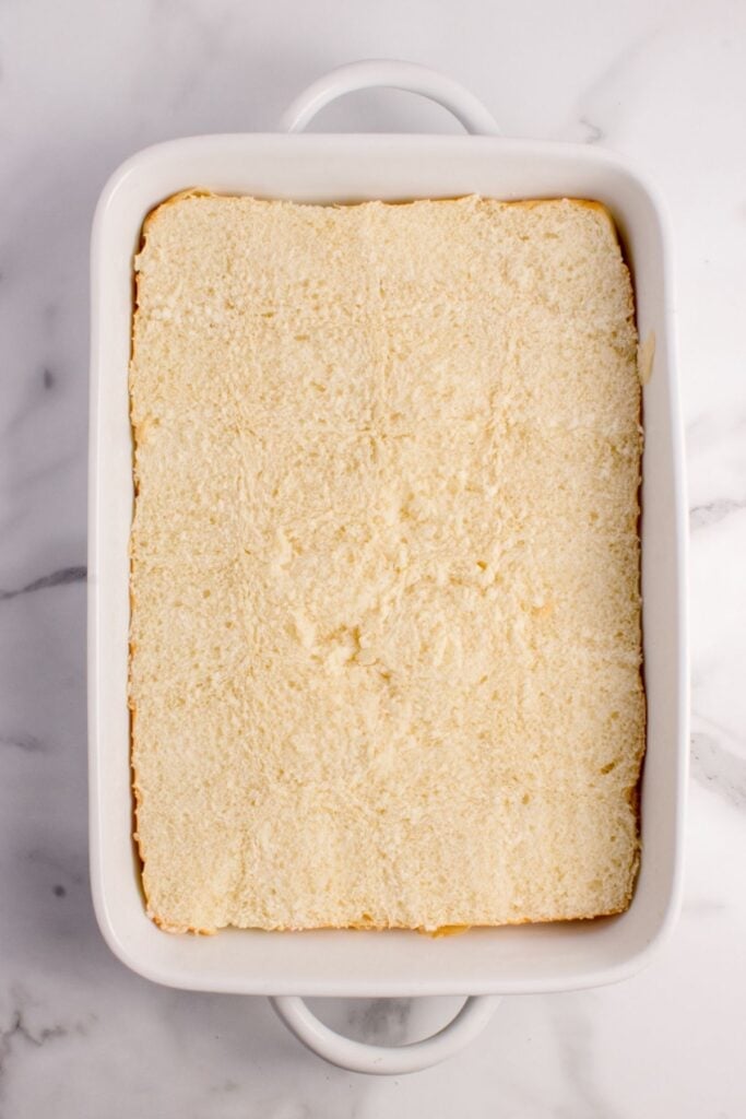 Sliced brick of slider buns are placed in a baking pan.