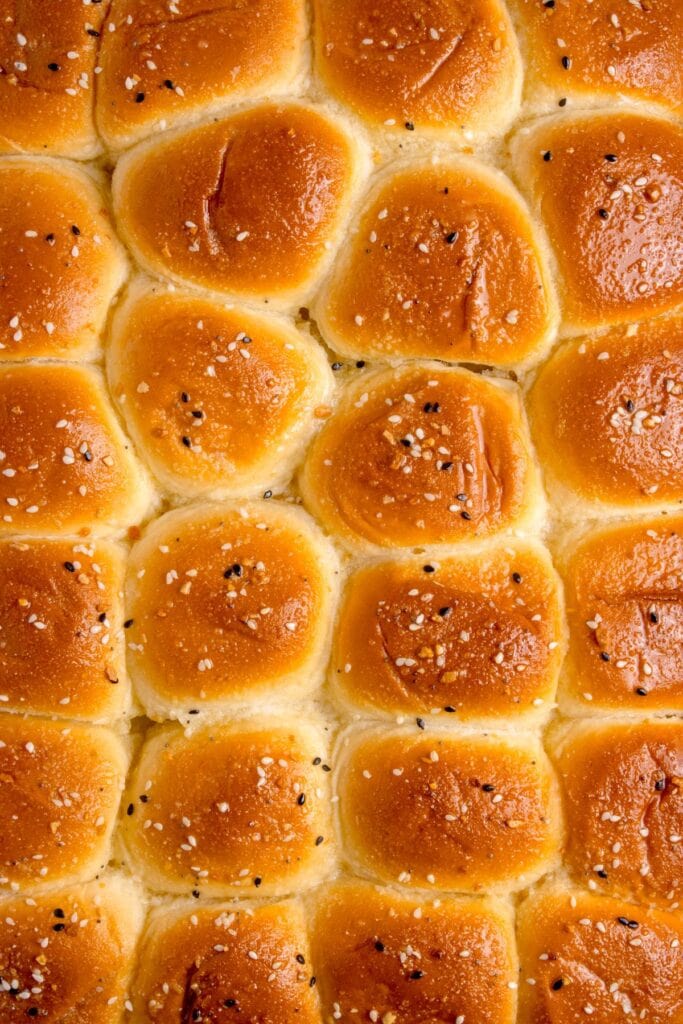 Tops of roast beef sliders with butter and everything bagel seasoning.