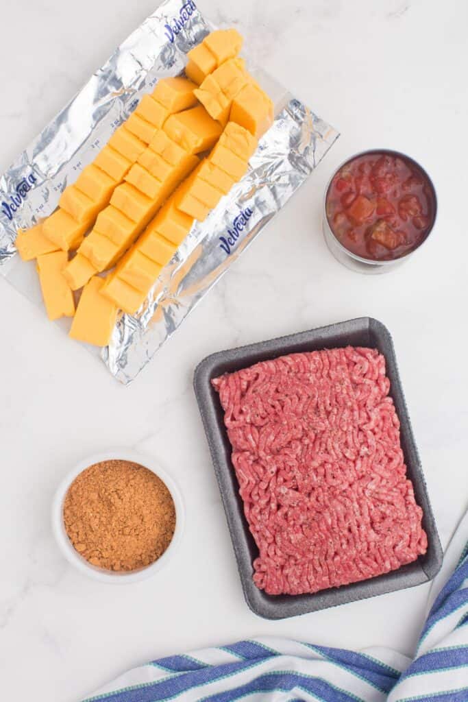 Ingredients for Rotel Cheese Dip: Velveeta cheese, Rotel tomatoes, taco seasoning, and ground beef.