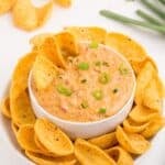 Rotel cheese dip in a white bowl surrounded by a plate of corn chips.