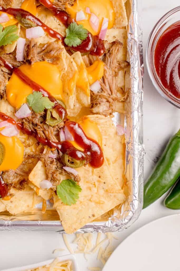 An aluminum foil covered pan with nachos on it.