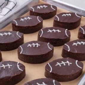 A parchment lined baking sheet with completed football brownies on it.