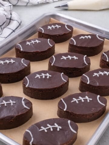 A parchment lined baking sheet with completed football brownies on it.