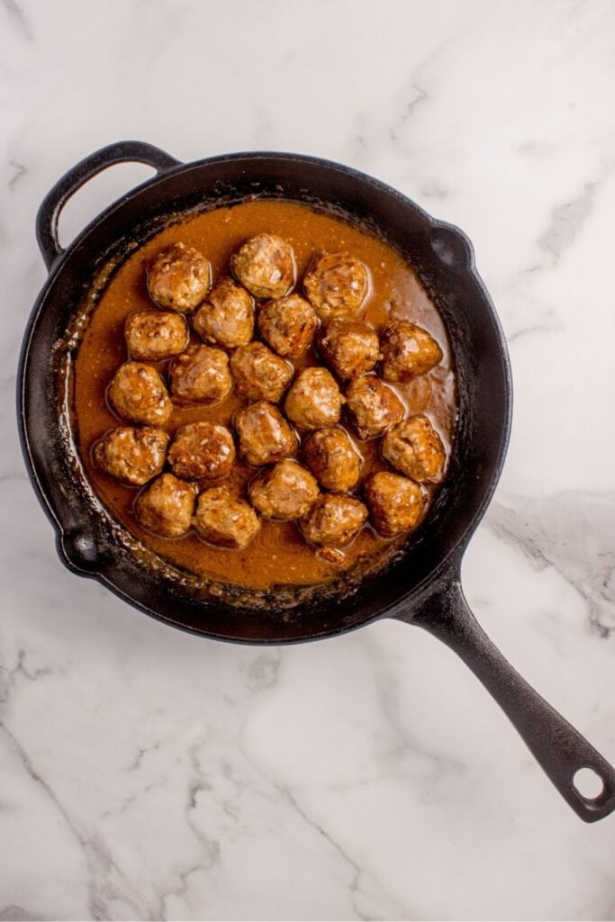 Meatballs and gravy in a cast iron pan.