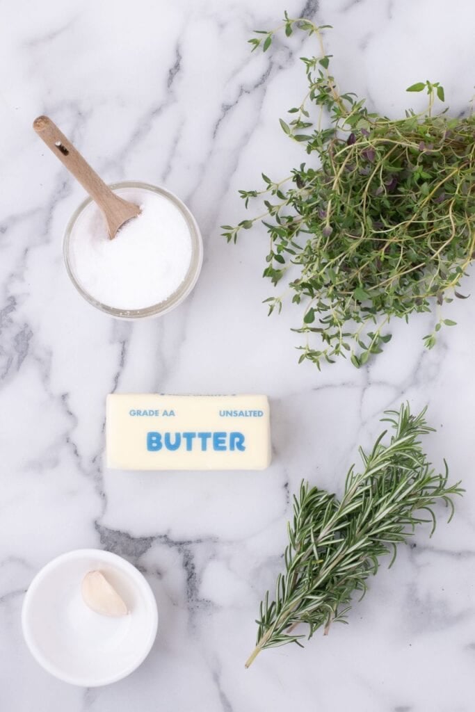 Ingredients for steak butter: garlic, unsalted butter, salt, fresh thyme, and fresh rosemary.