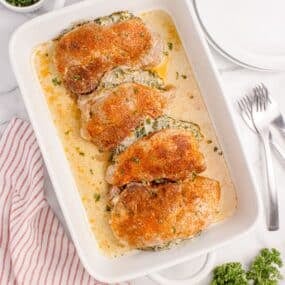 Four stuffed pork chops in a white baking dish.