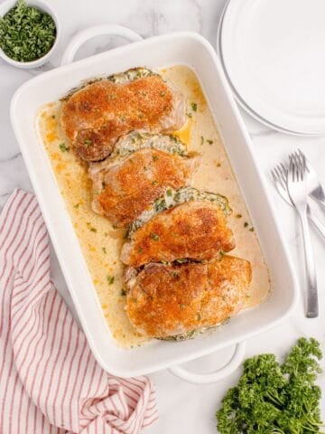 Four stuffed pork chops in a white baking dish.