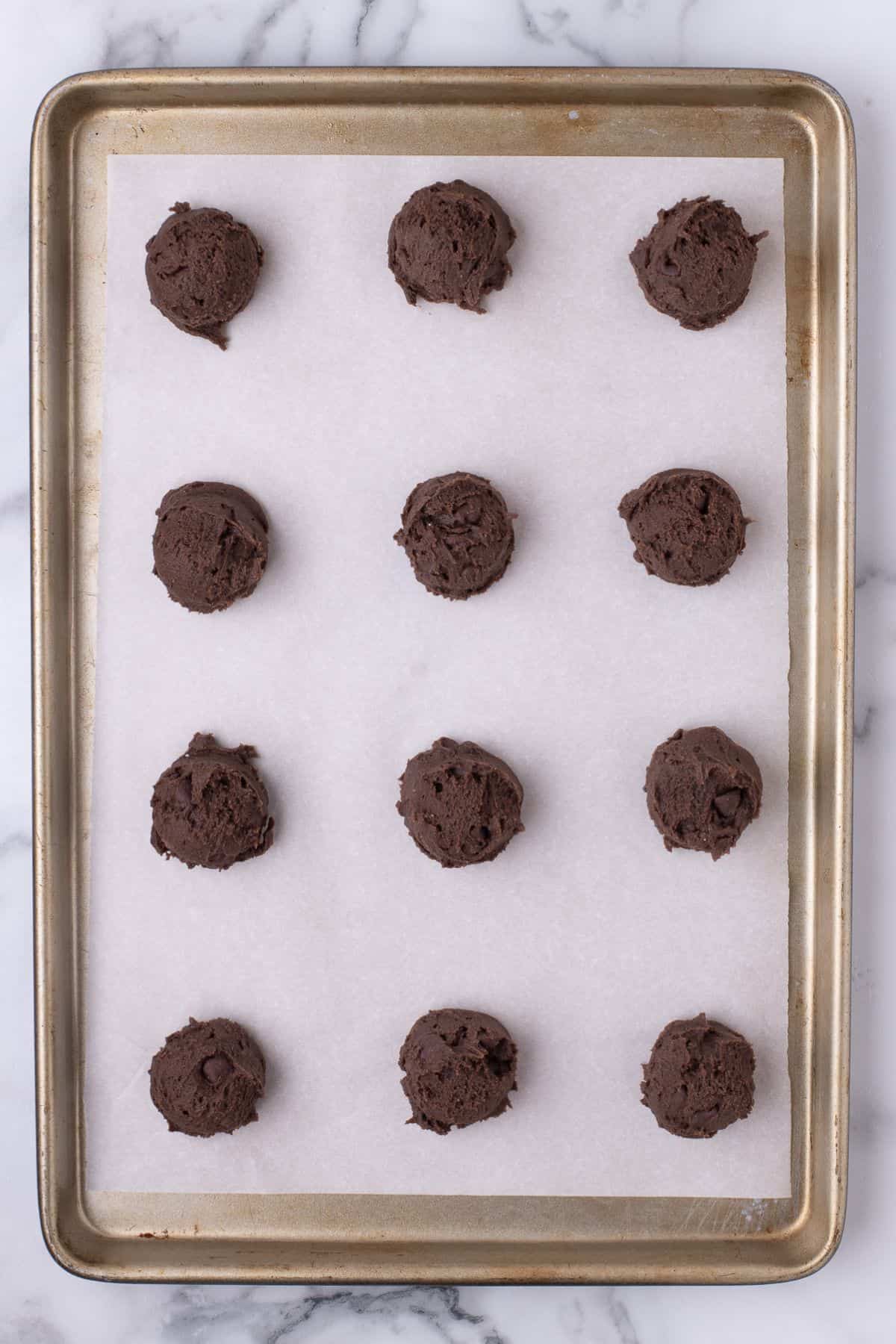 Brownie mix cookies scooped onto a baking sheet with parchment paper about to be baked.