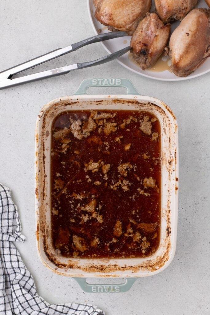 Chicken thighs removed from baking dish, showing the remaining marinade.