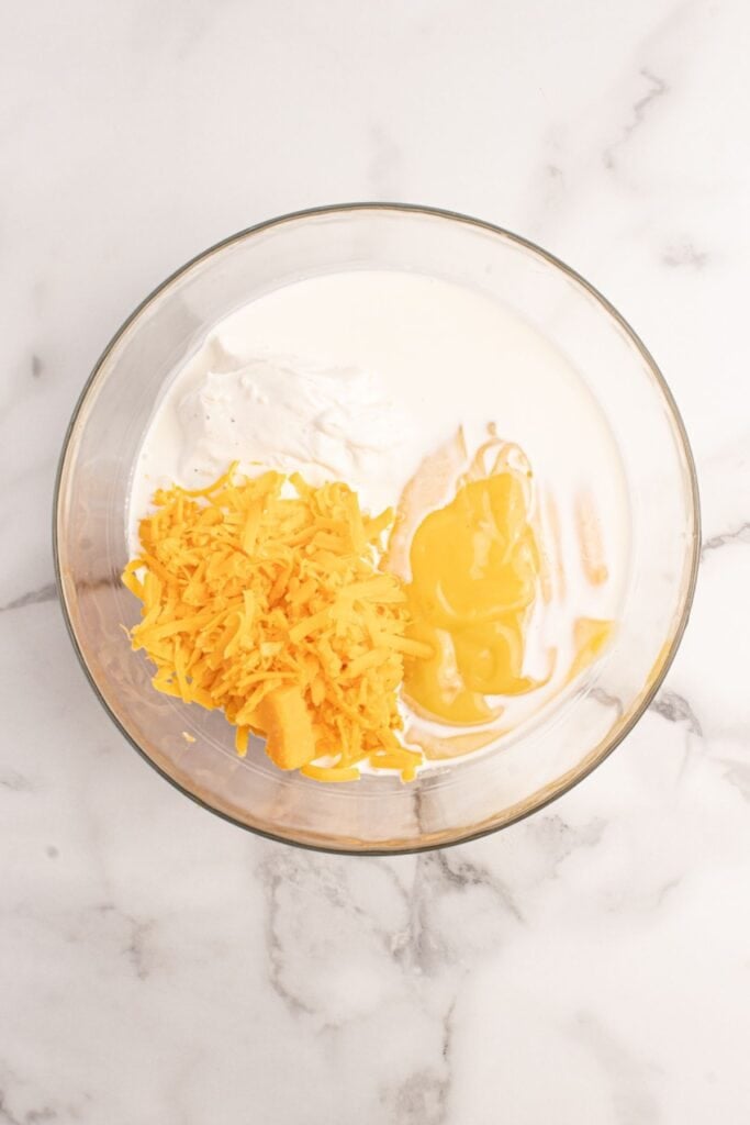 Glass bowl with ingredients for the cheese mixture for scalloped potatoes.