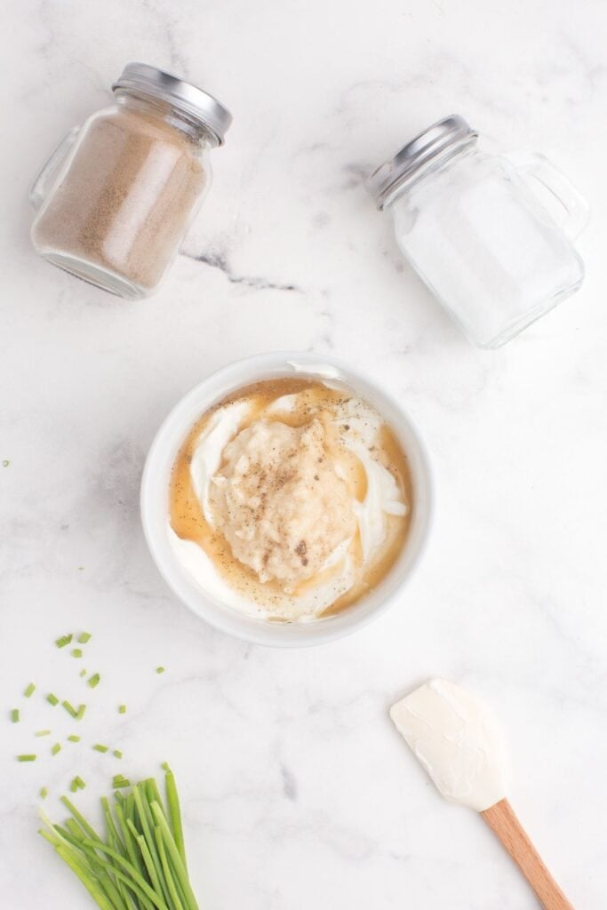 White bowl with sour cream, apple cider vinegar, horseradish, salt, and pepper.