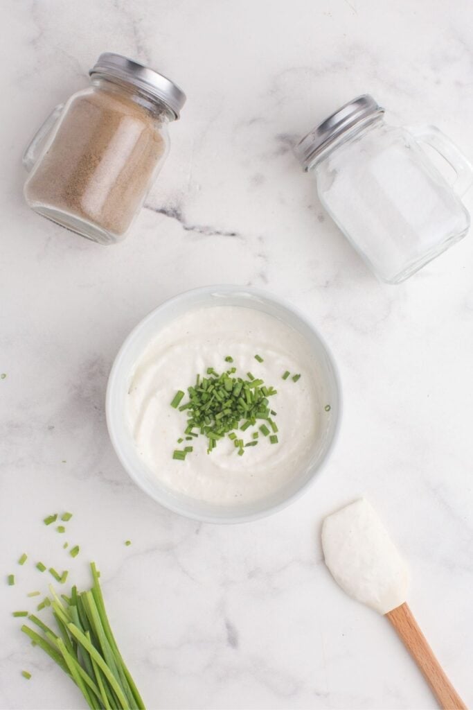 A small pile of chopped chives is in the center of the bowl of horseradish sauce.