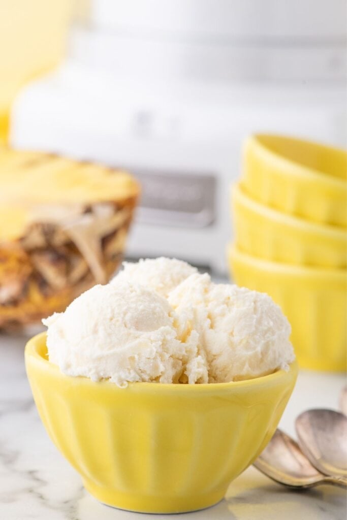 Pineapple ice cream in a yellow bowl.