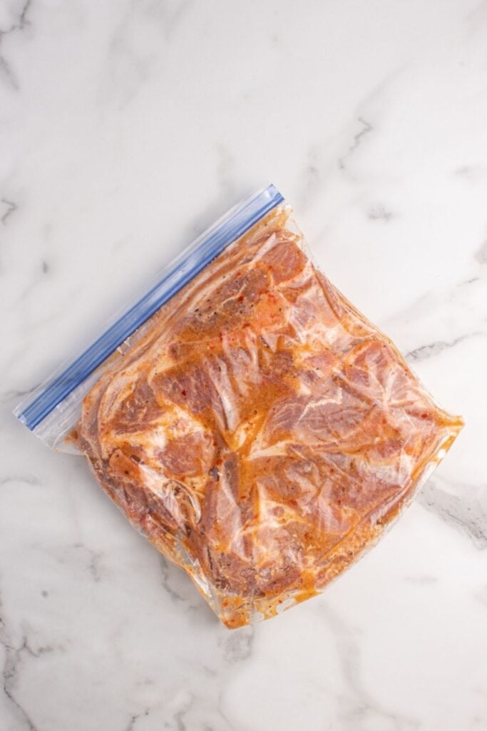 Pork steaks marinating in a zip top bag.