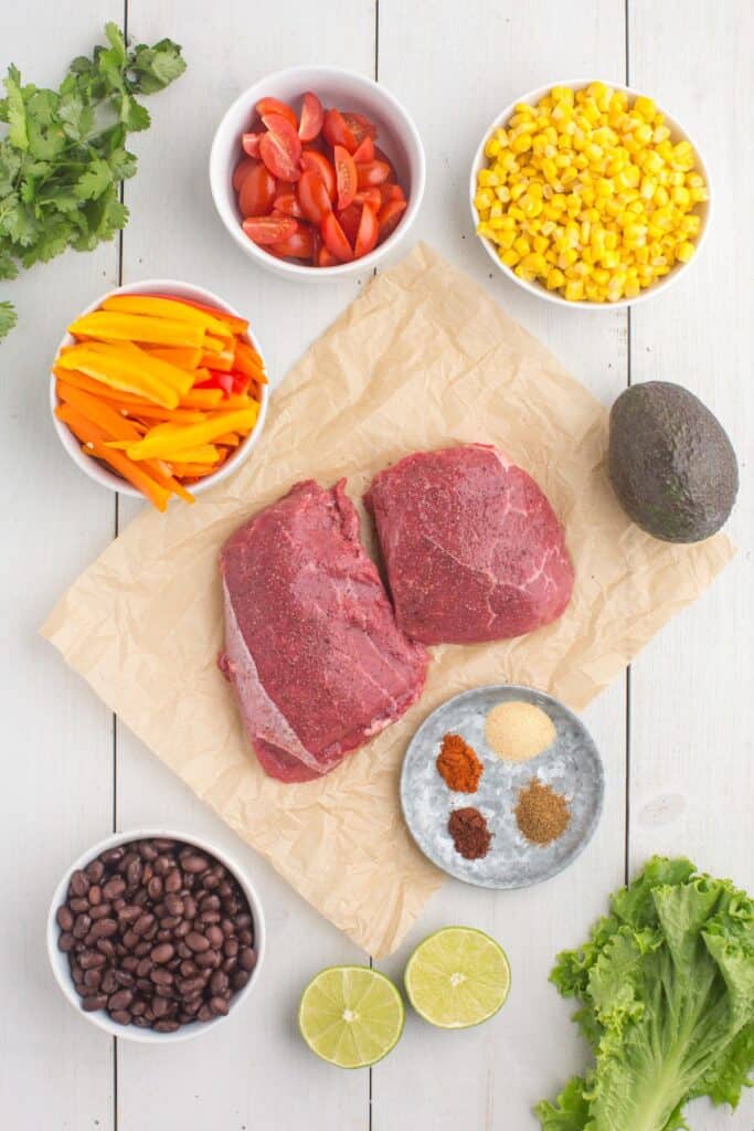 Ingredients for steak bowls: Flank Steak, limes, chili powder, salt, garlic powder, cumin , paprika, cherry tomatoes, bell peppers, black beans, corn, olive oil, avocado, lettuce, and premade rice.