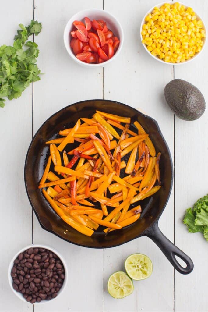 Bell peppers cooking in a cast iron pan.