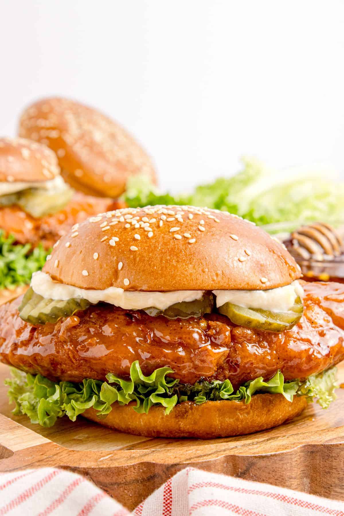 Completed hot honey chicken sandwich on a wooden cutting board.