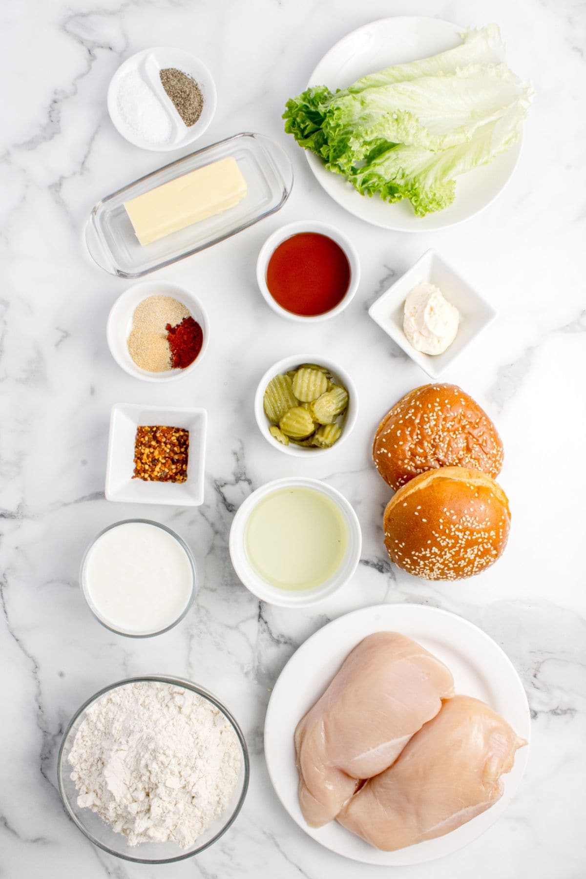 Ingredients for hot honey chicken sandwich: flour, sweet paprika, garlic powder, onion powder, salt, pepper, buttermilk, chicken breasts, oil, hot honey, butter, chili flakes, brioche buns, mayonnaise, lettuce leaves, and pickles.