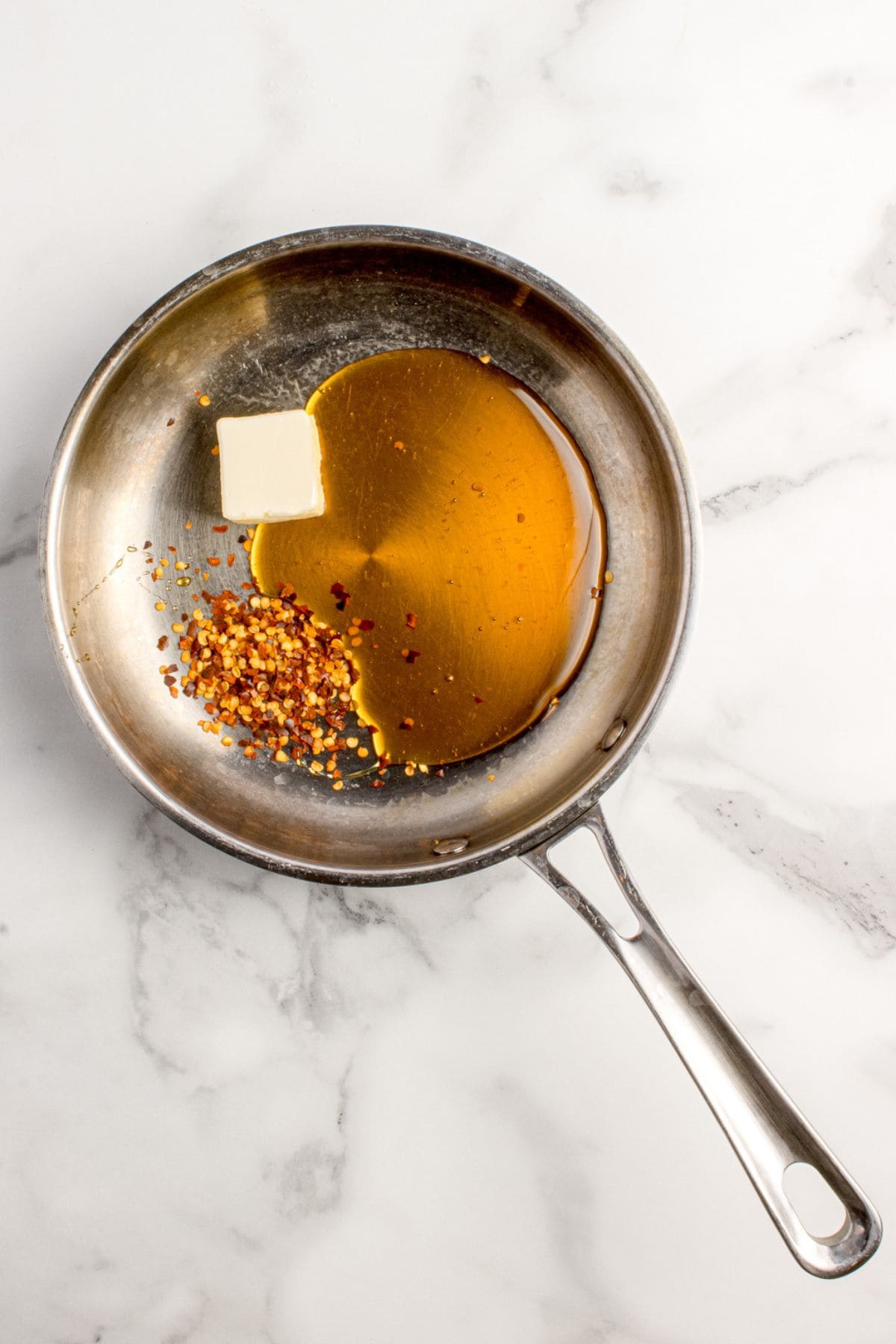 Hot honey, chili flakes, and butter combined in a small saucepan.