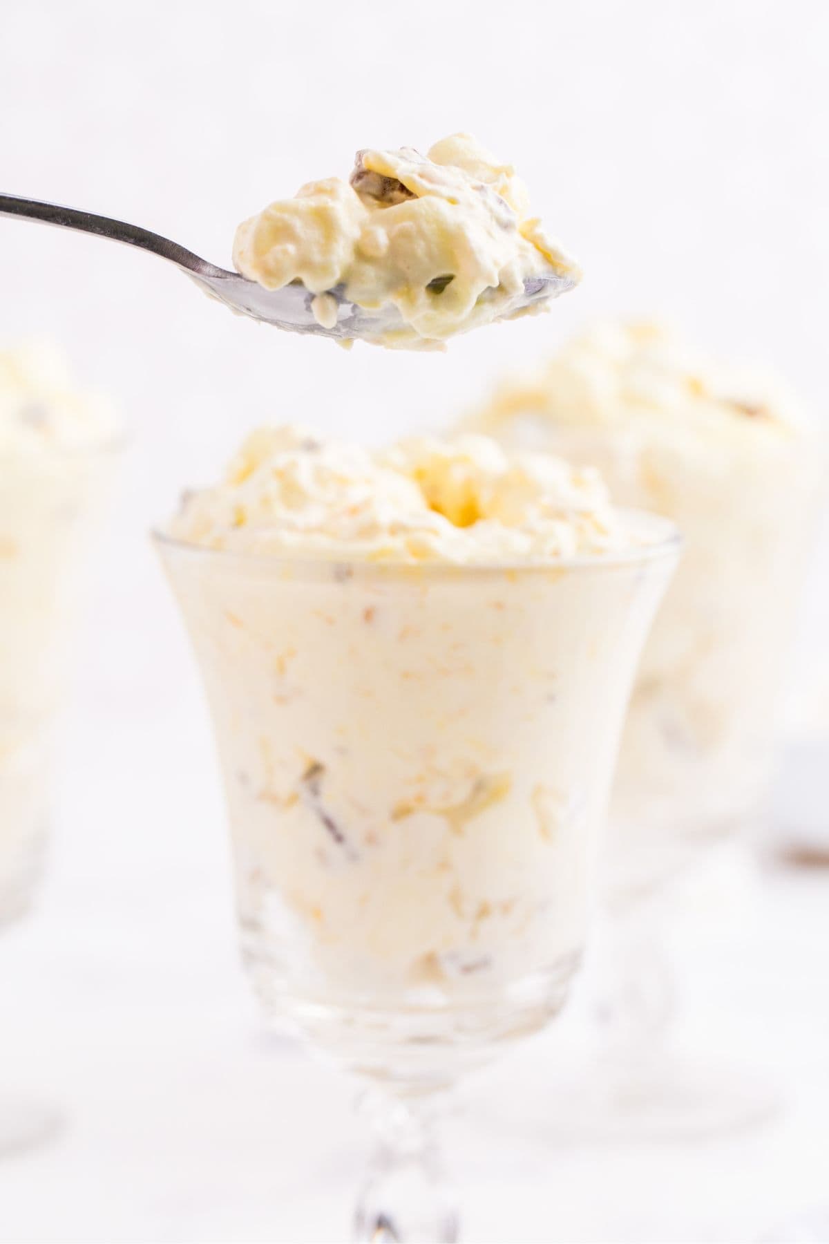 Completed pineapple fluff in a glass with a spoon lifting a bite out to show detail.