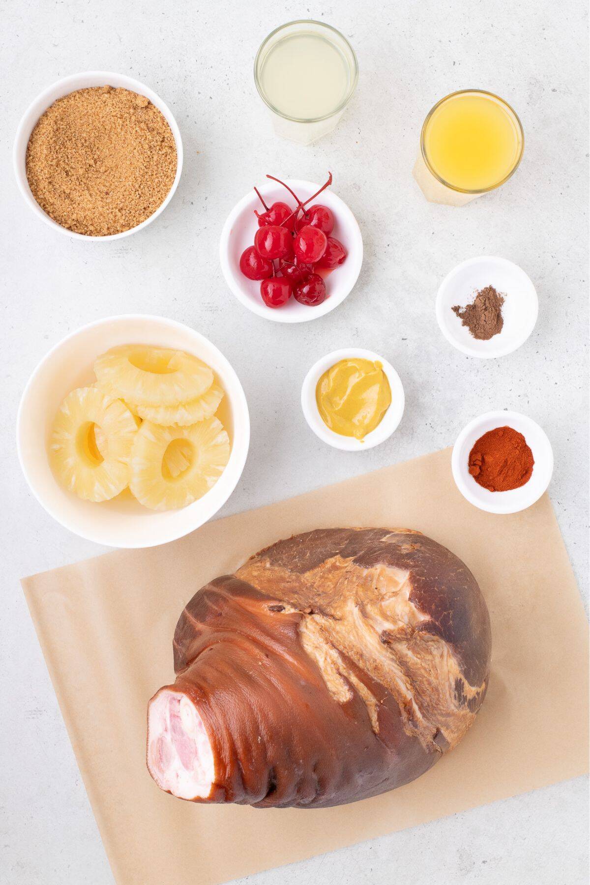 Ingredients for pineapple glazed ham: ham, canned pineapple rings, brown sugar, pineapple juice, maraschino cherries, ground cloves, paprika, and yellow mustard.
