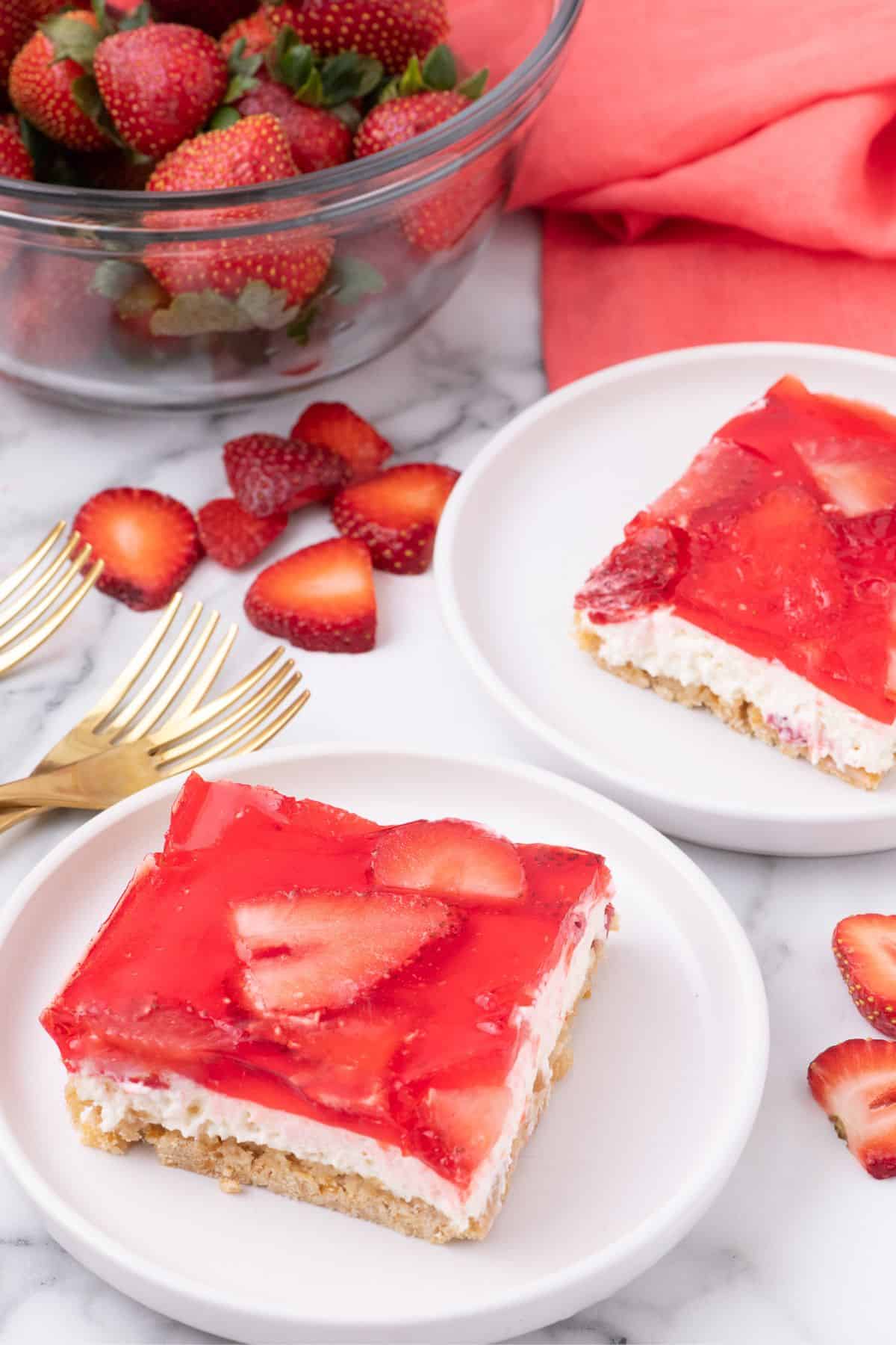 Two slices of strawberry pretzel salad on white plates.