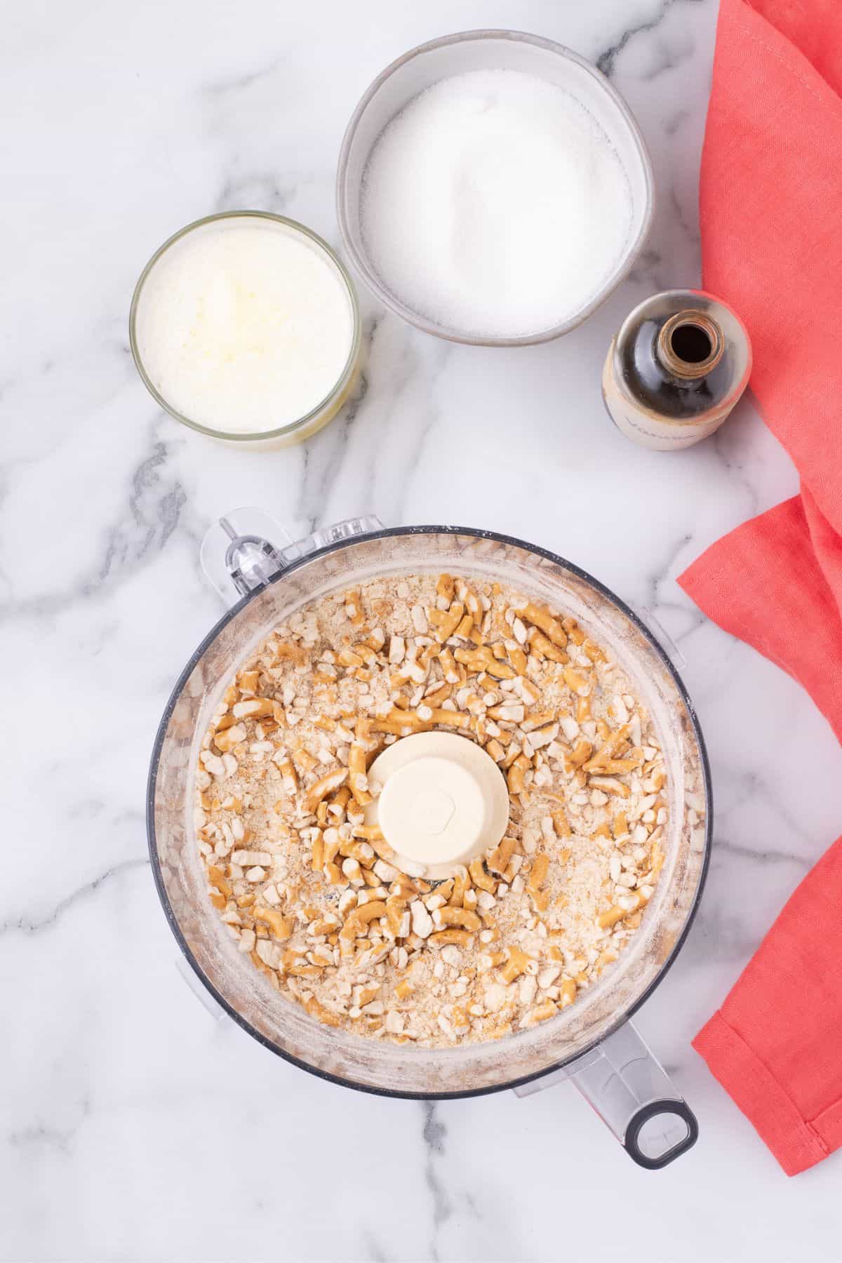 Pretzels are broken down in a food processor with butter, sugar, and vanilla.