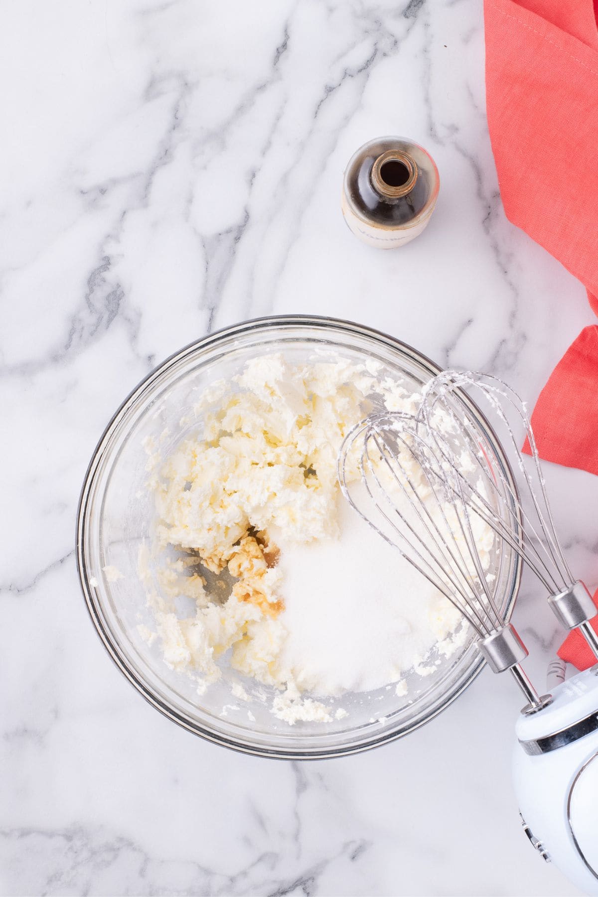 Cream cheese, sugar, and vanilla whipped together in a glass mixing bowl.