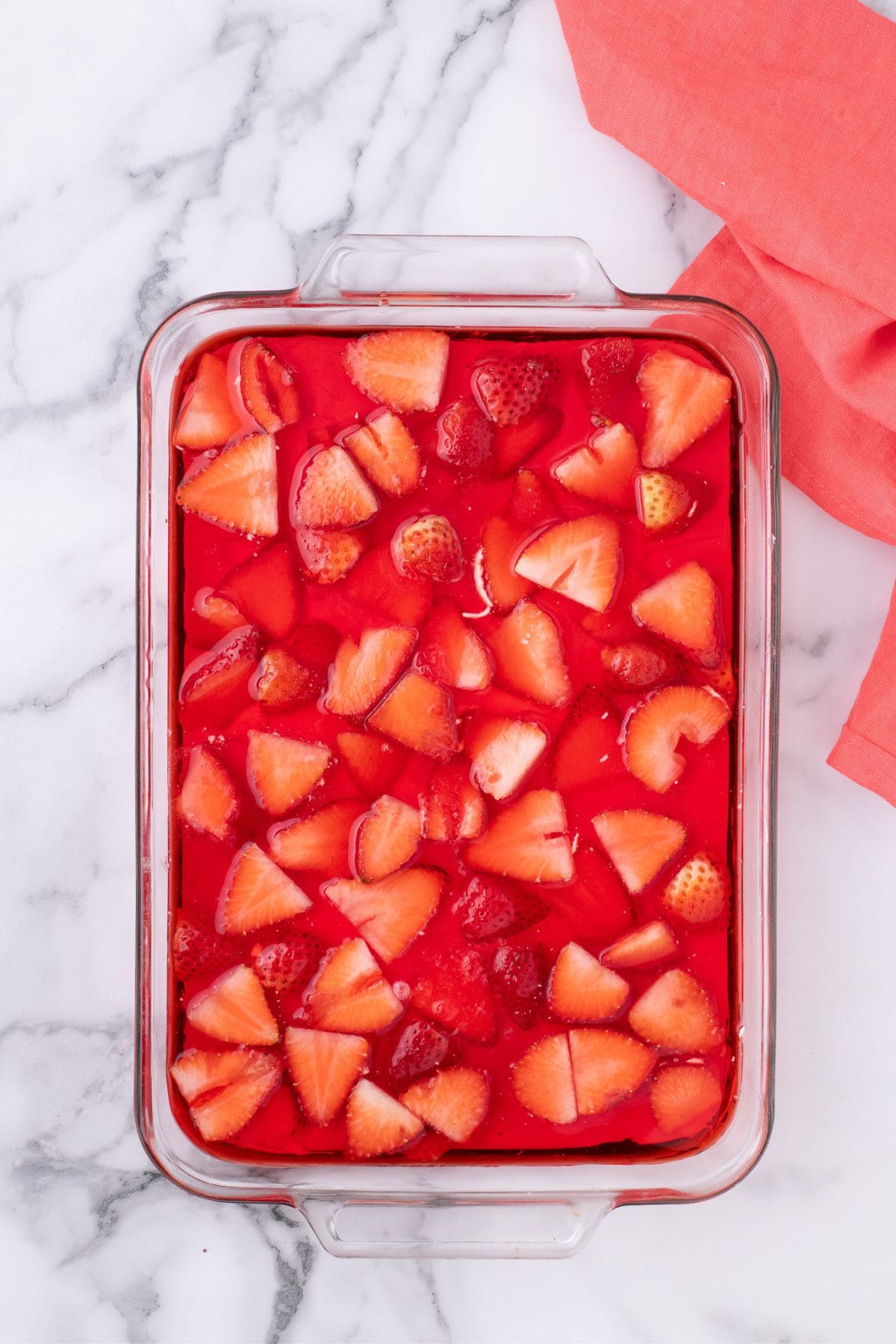 Liquid Jello is poured over the top of the strawberries.