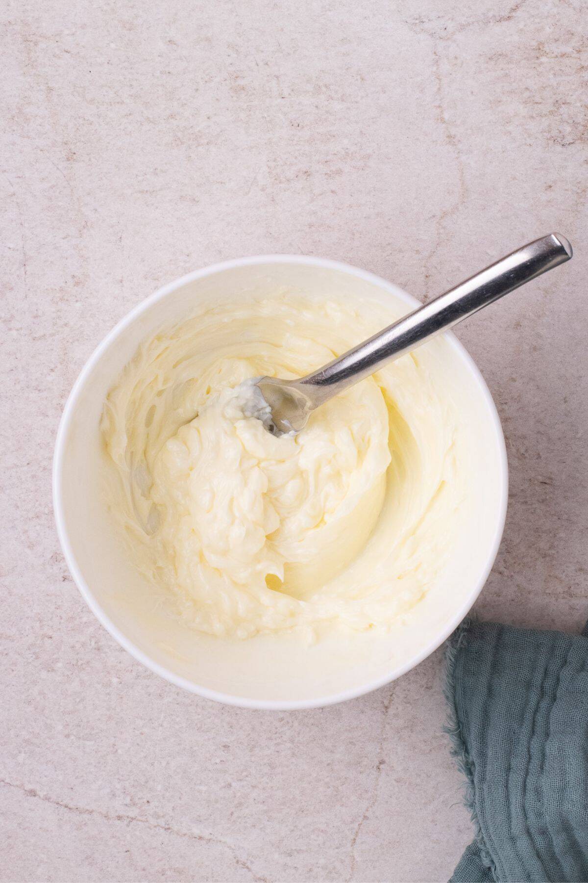 Softened butter in a white bowl with a fork.