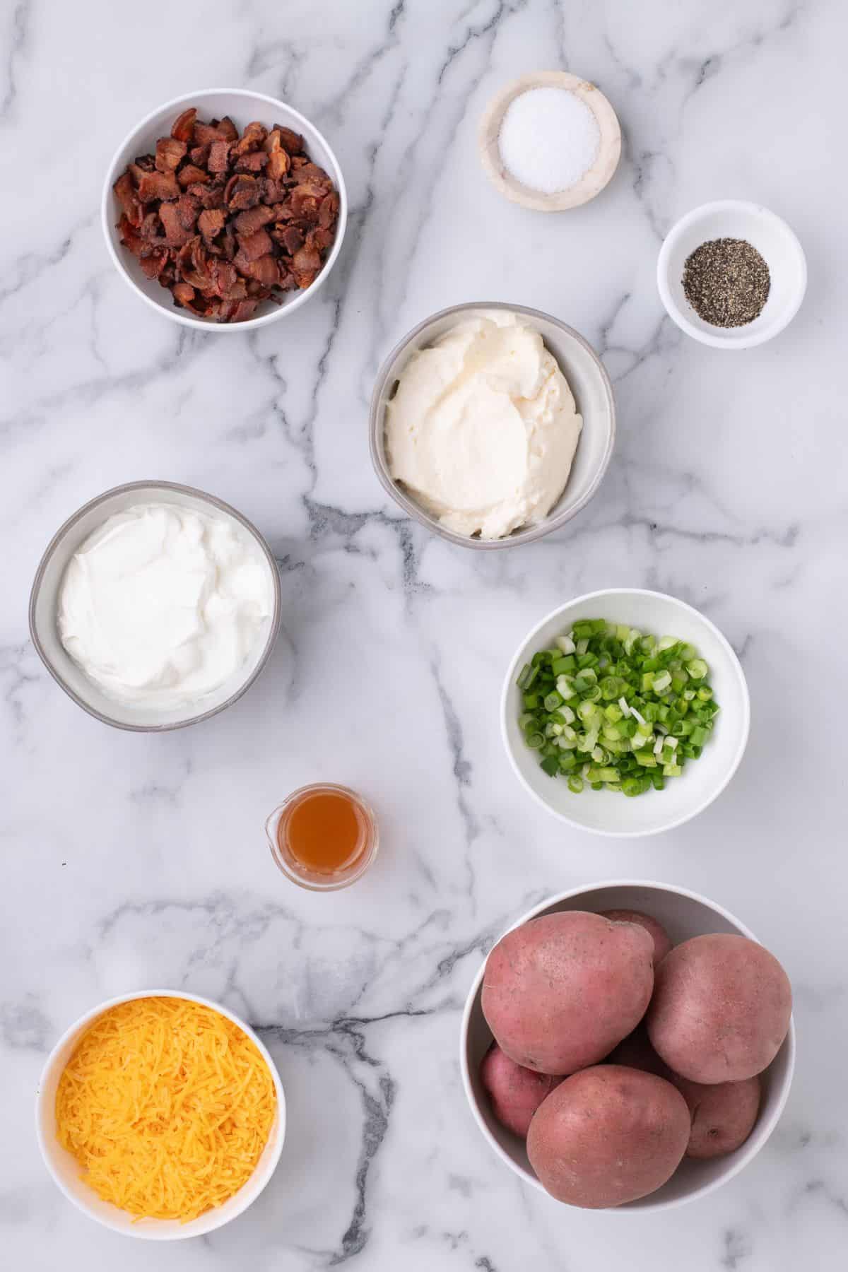 Ingredients for loaded potato salad: potatoes, sour cream, mayonnaise, apple cider vinegar, salt, black pepper, cheddar cheese, bacon bits, and green onions