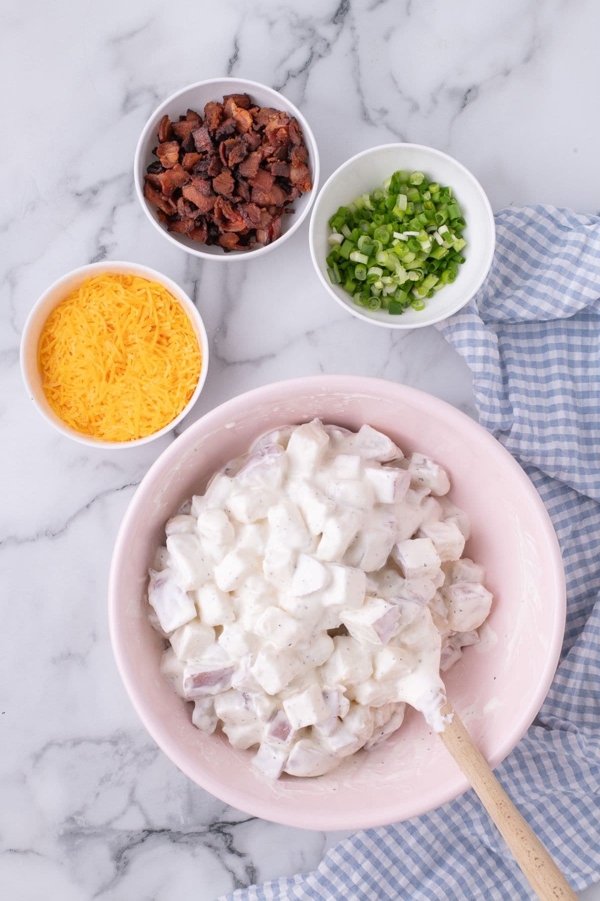 Large mixing bowl with potatoes coated in the sour cream mixture.