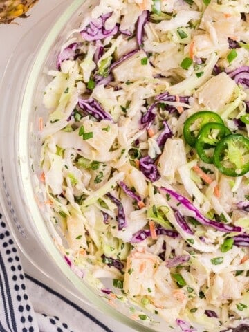 Pineapple coleslaw in a glass serving bowl.